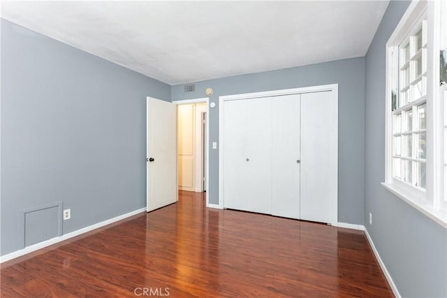 unfurnished bedroom featuring a closet and dark hardwood / wood-style flooring