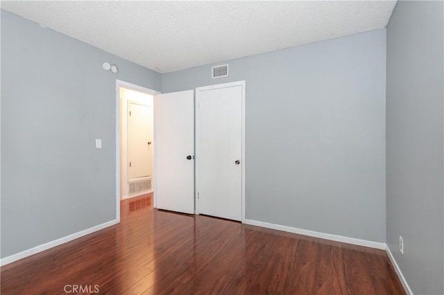 unfurnished bedroom featuring a textured ceiling and dark hardwood / wood-style floors