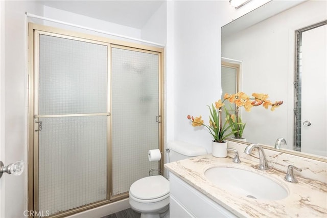 bathroom with vanity, toilet, and a shower with shower door