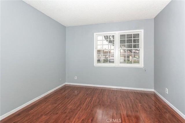 unfurnished room featuring dark hardwood / wood-style flooring and a textured ceiling