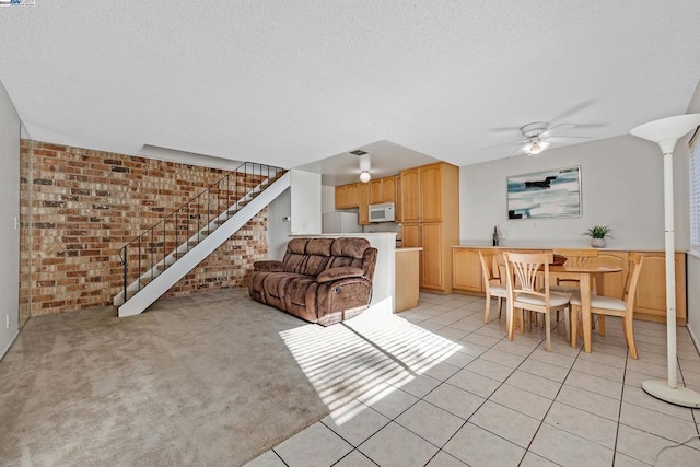 living room with ceiling fan, light tile patterned floors, and brick wall