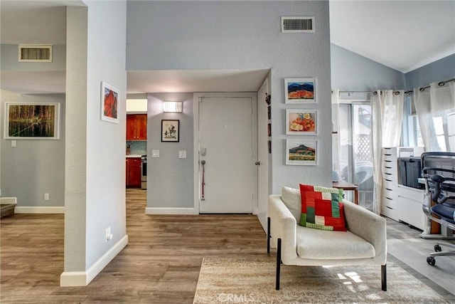 foyer entrance featuring high vaulted ceiling and light hardwood / wood-style flooring