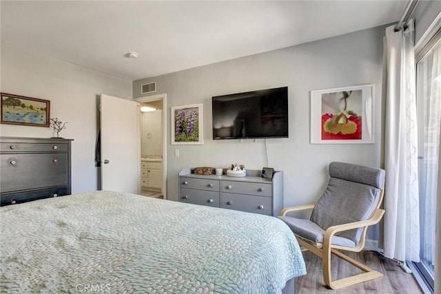 bedroom with ensuite bathroom and hardwood / wood-style floors