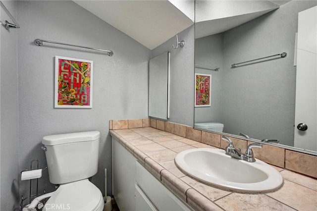 bathroom featuring vanity, toilet, and lofted ceiling