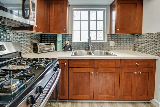 kitchen with decorative backsplash, light hardwood / wood-style floors, sink, and stainless steel appliances