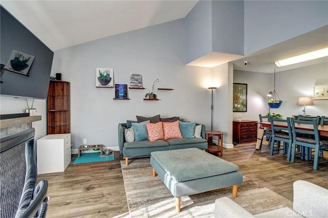 living room with a fireplace, high vaulted ceiling, and hardwood / wood-style flooring