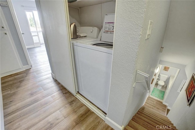 clothes washing area with washer / dryer and light wood-type flooring