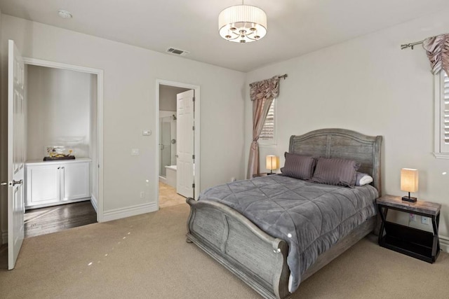 bedroom featuring ensuite bathroom, light colored carpet, and a notable chandelier