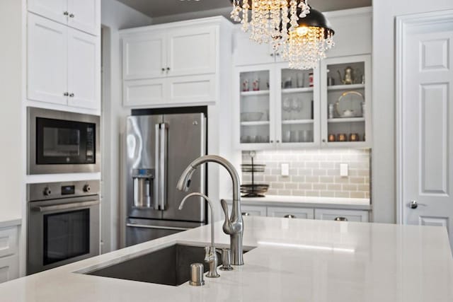 kitchen with decorative light fixtures, sink, appliances with stainless steel finishes, white cabinets, and a chandelier