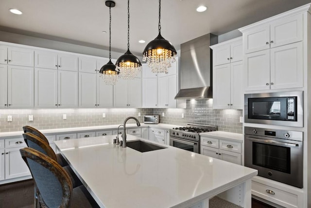 kitchen with stainless steel appliances, backsplash, pendant lighting, wall chimney exhaust hood, and sink