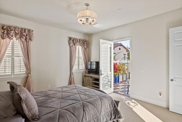 carpeted bedroom with access to outside, an inviting chandelier, and multiple windows