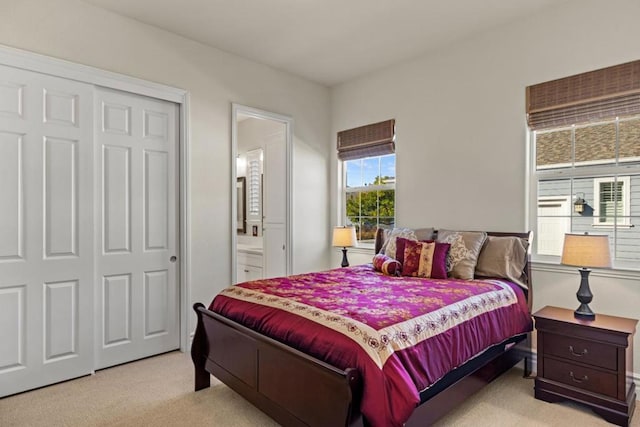 bedroom with ensuite bath, light carpet, and a closet