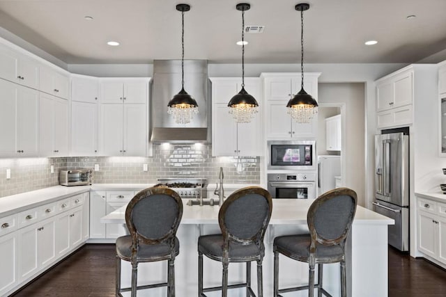 kitchen featuring white cabinetry, wall chimney range hood, appliances with stainless steel finishes, and tasteful backsplash