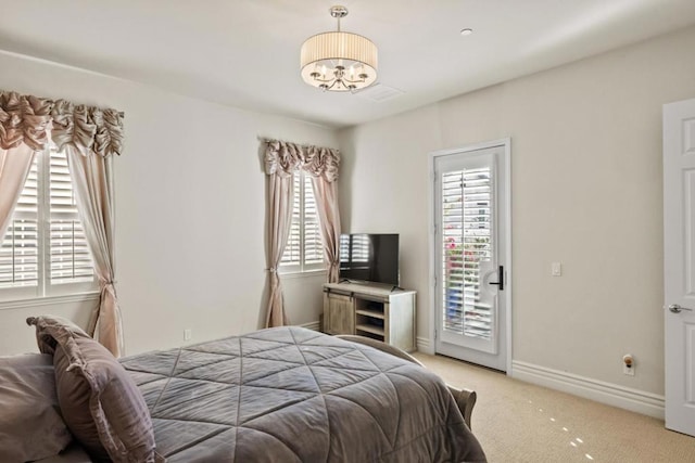 carpeted bedroom with access to exterior and a notable chandelier