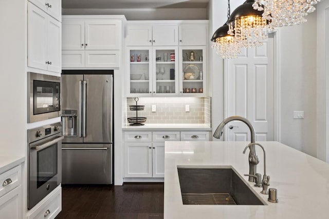 kitchen featuring sink, white cabinetry, hanging light fixtures, stainless steel appliances, and a chandelier