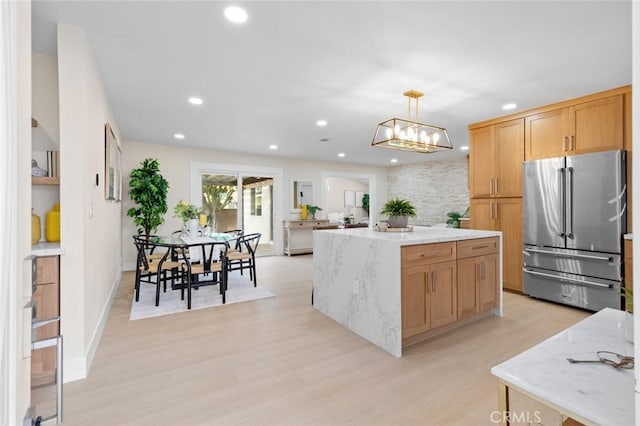 kitchen with high end refrigerator, a kitchen island, decorative light fixtures, light hardwood / wood-style floors, and a chandelier