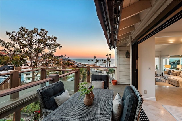 balcony at dusk featuring a water view