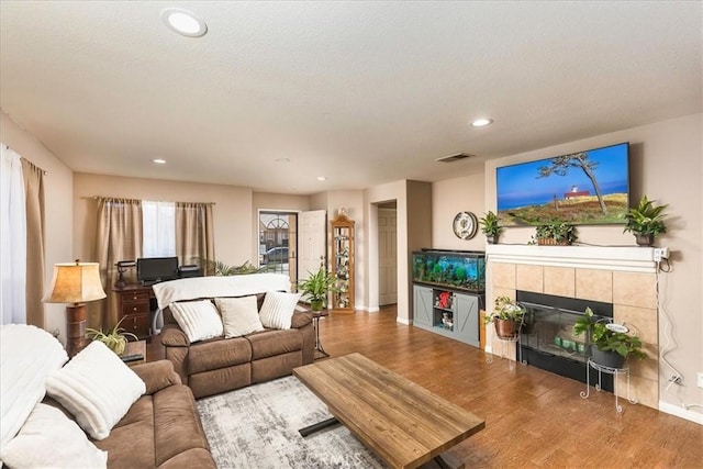 living room with a tile fireplace and hardwood / wood-style flooring