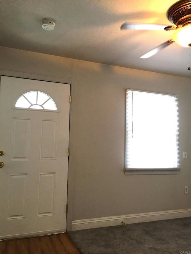 foyer entrance with ceiling fan and dark wood-type flooring