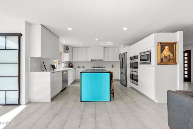 kitchen with white cabinets, a healthy amount of sunlight, a kitchen island, and stainless steel appliances