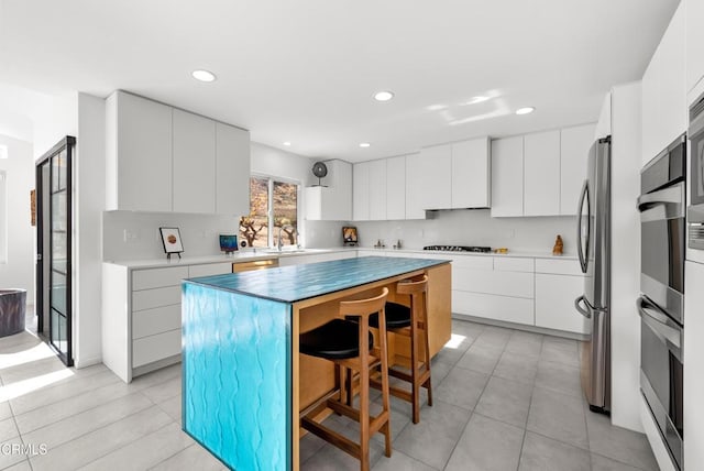 kitchen featuring white cabinets, a breakfast bar, a center island, and sink