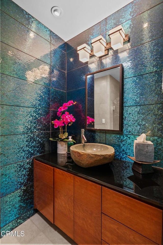 bathroom featuring vanity and tile walls