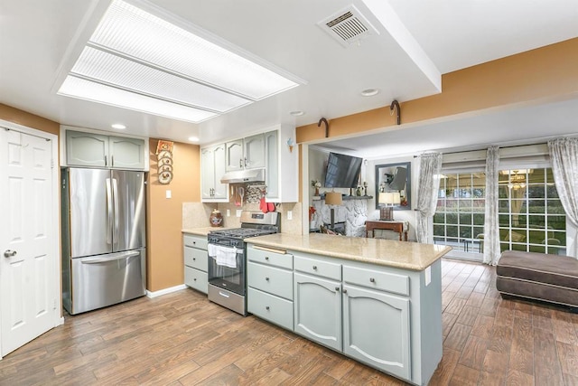 kitchen featuring kitchen peninsula, dark hardwood / wood-style flooring, stainless steel appliances, and backsplash