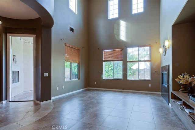 unfurnished living room featuring light tile patterned flooring and a towering ceiling