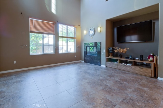 unfurnished living room with light tile patterned flooring and a high ceiling