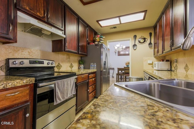 kitchen featuring a chandelier, light stone counters, appliances with stainless steel finishes, and tasteful backsplash