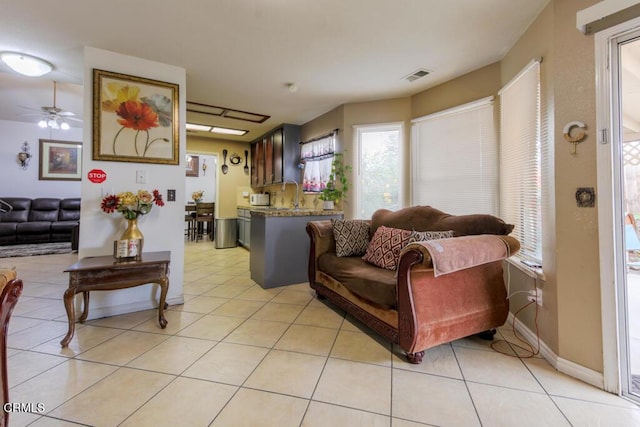 tiled living room featuring ceiling fan and sink