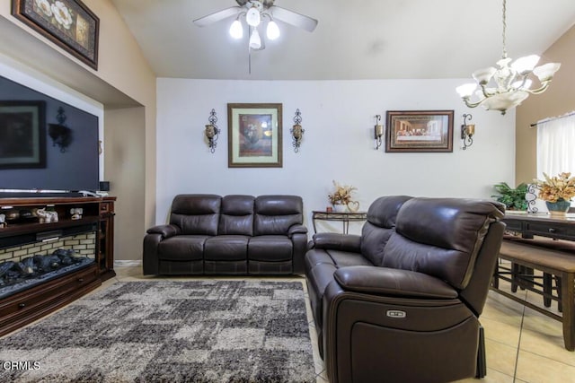 tiled living room with ceiling fan with notable chandelier and vaulted ceiling