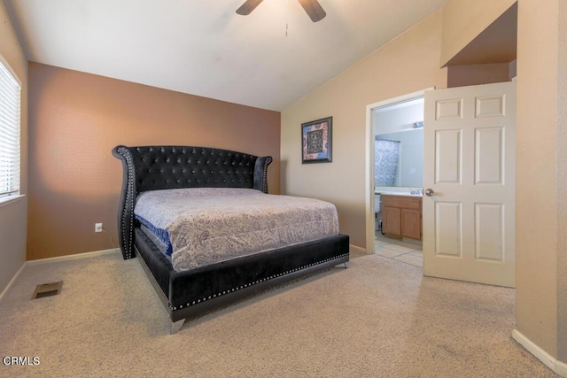 bedroom with light carpet, connected bathroom, vaulted ceiling, and ceiling fan