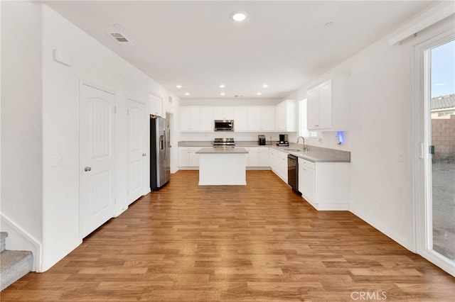 kitchen featuring white cabinets, a center island, light wood-type flooring, and appliances with stainless steel finishes