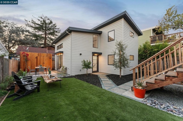 back house at dusk with a yard and a patio