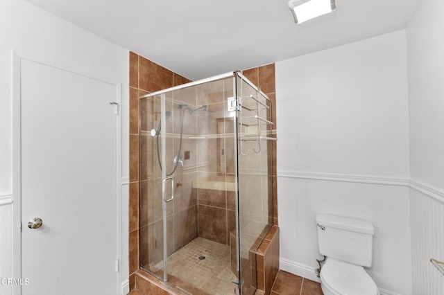 bathroom featuring tile patterned flooring, toilet, and a shower with shower door