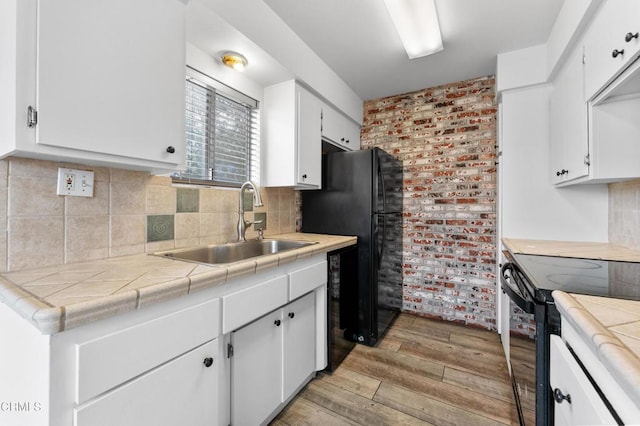 kitchen with tile countertops, sink, light hardwood / wood-style flooring, electric range oven, and white cabinetry