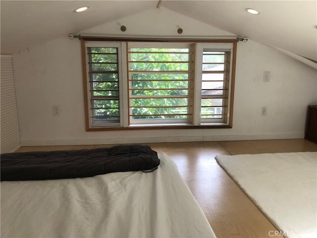 unfurnished bedroom with hardwood / wood-style floors and vaulted ceiling with beams