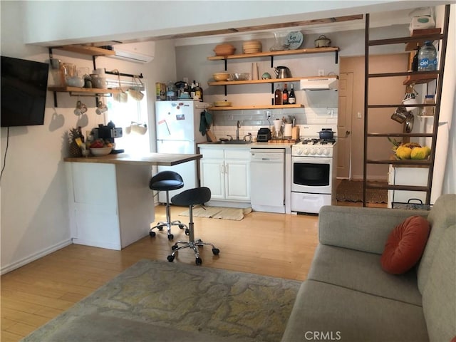 kitchen featuring decorative backsplash, light wood-type flooring, white appliances, a wall mounted AC, and sink