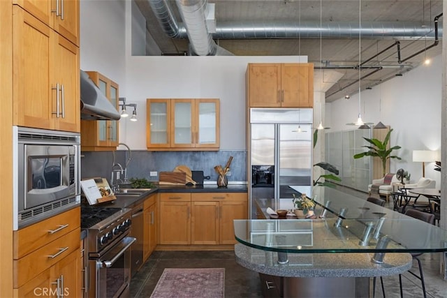 kitchen featuring backsplash, sink, hanging light fixtures, built in appliances, and a towering ceiling