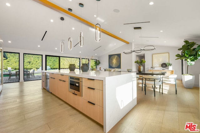 kitchen featuring light brown cabinets, lofted ceiling with beams, a spacious island, hanging light fixtures, and light hardwood / wood-style floors