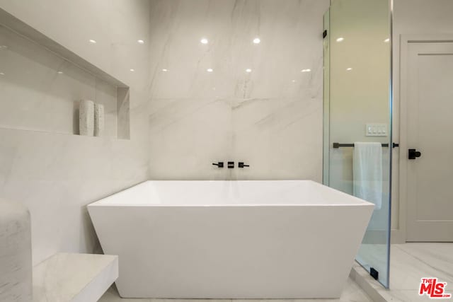 bathroom with a bathtub and tile walls