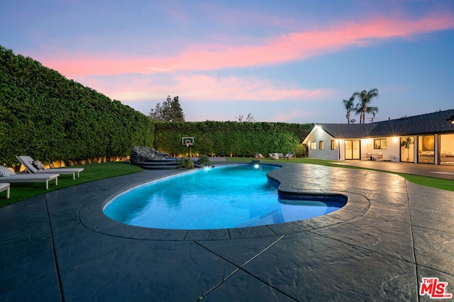 pool at dusk featuring a patio