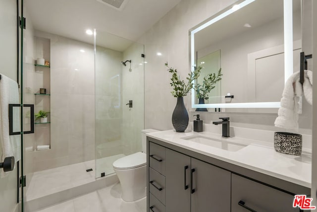 bathroom featuring tile patterned flooring, vanity, a shower with shower door, and toilet