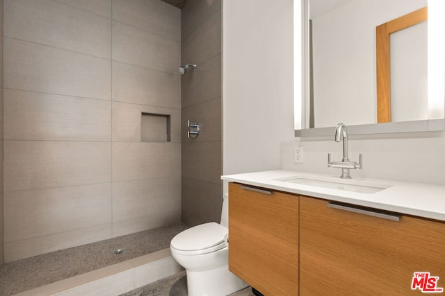 bathroom featuring tile patterned floors, vanity, toilet, and tiled shower