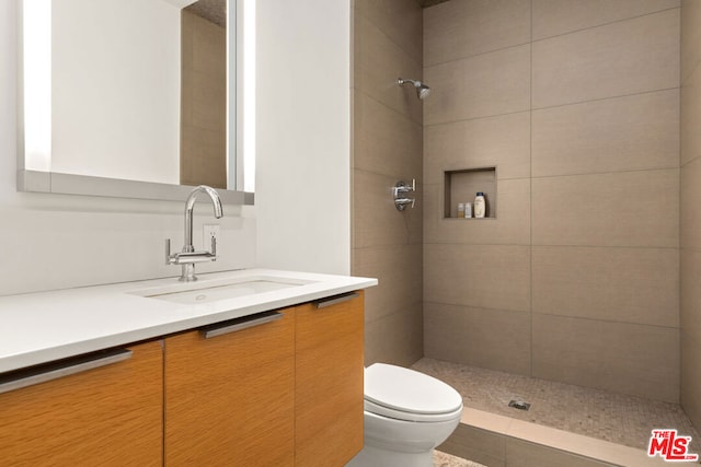 bathroom featuring vanity, toilet, and a tile shower