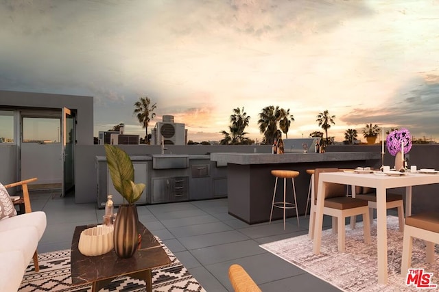 patio terrace at dusk with exterior kitchen and a wet bar