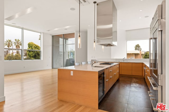 kitchen with hardwood / wood-style floors, sink, wine cooler, hanging light fixtures, and appliances with stainless steel finishes