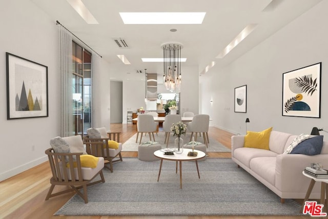 living room featuring a skylight, light wood-type flooring, and an inviting chandelier