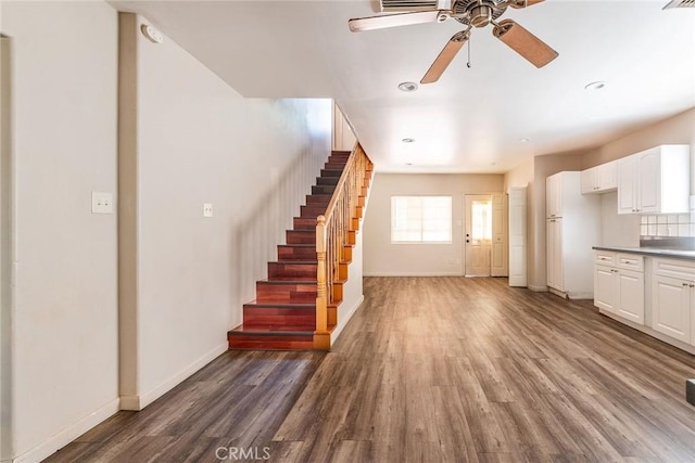 unfurnished living room featuring ceiling fan and dark wood-type flooring